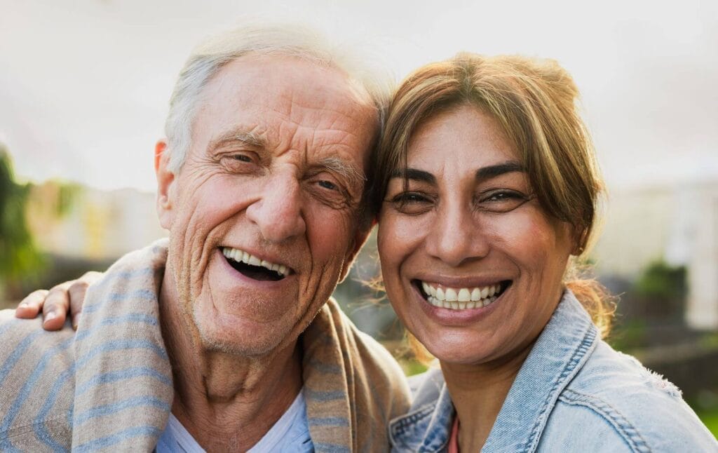 A woman and and older adult man smile.