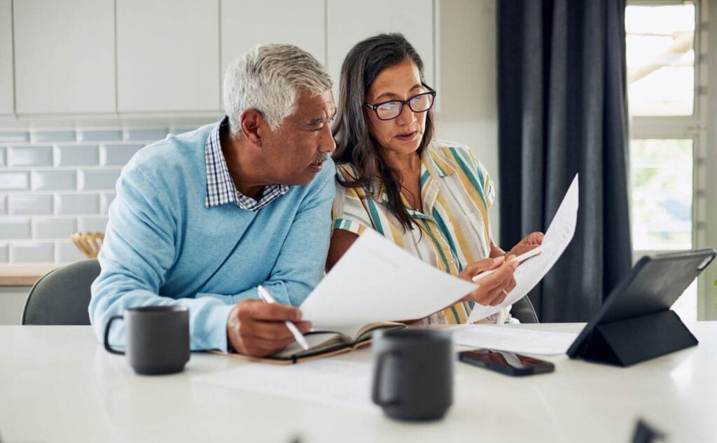 An older adult man and woman sit at a counter reviewing documents.