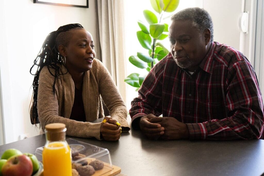 A woman sits at a counter talking with her older adult father.