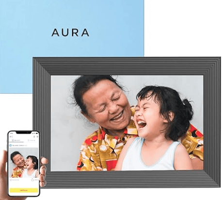 Product image of a picture frame displaying a photo of a young child laughing with an older adult woman. Image also contains smartphone and photo in frame along with product box.